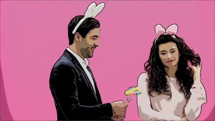 年轻夫妇在粉红色背景上有创意。头上有一只兔子耳朵。在此期间，妻子手里拿着装饰性的五彩蛋。轻轻地亲吻她