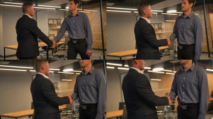 两名同事在现代商务办公室内握手