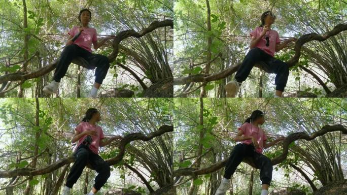 快乐的亚洲女孩在竹林的树枝上放松和乐趣，生活方式的概念。
