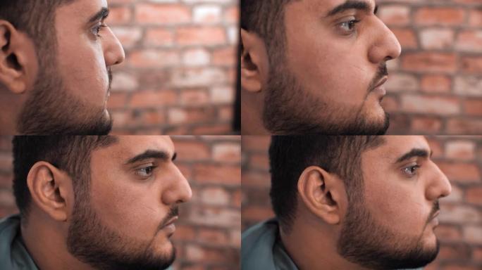 在砖背景上关闭阿拉伯男性面部轮廓视图。肖像黑胡子英俊的男人。大胡子的脸。