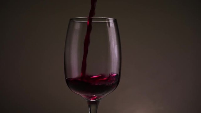 将红酒倒入深色背景的玻璃杯中。