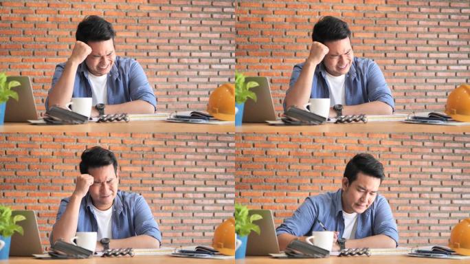 认真对待亚洲建筑或工程师在办公室工作的笔记本电脑，生活方式概念。砖墙背景。