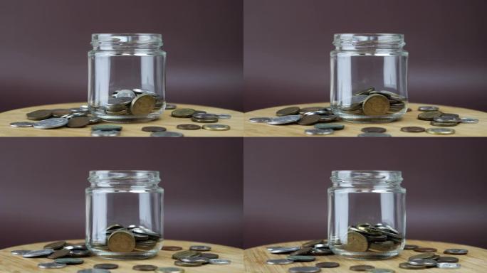 硬币落在玻璃罐里。钱币落入玻璃钱箱。省钱的概念。一堆硬币掉进罐子里。金融和经济概念
