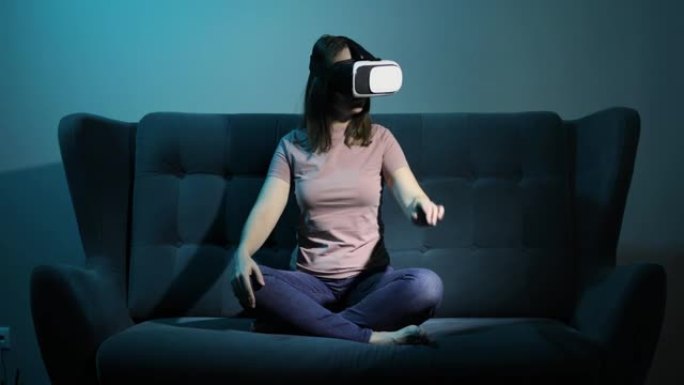 女人坐在沙发上，戴着虚拟现实眼镜，在空中抚摸手