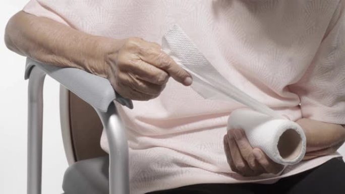 老年妇女在使用移动马桶座椅时撕下卫生纸