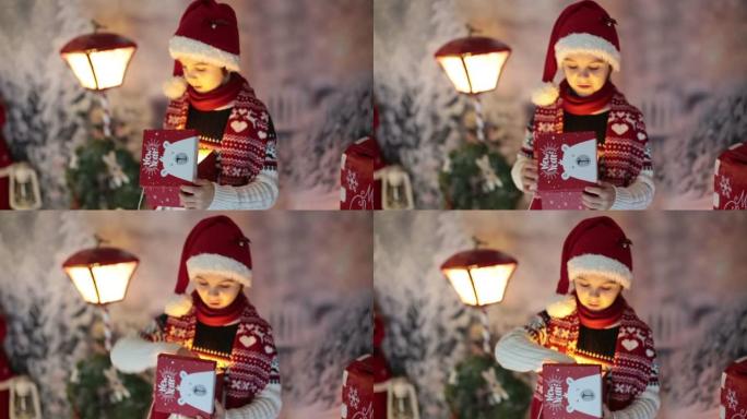 可爱的孩子，学校男孩，圣诞节的开幕礼物，他周围的装饰，户外拍摄，户外雪地拍摄