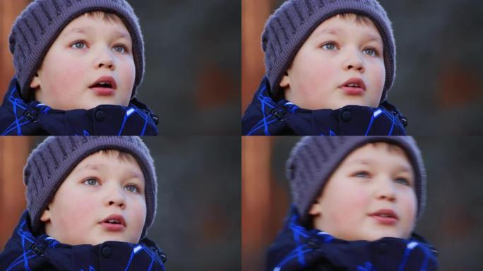 一个穿着夹克和帽子的快乐男孩的肖像，抬头仰望侧面。