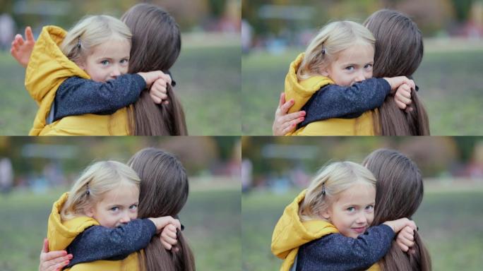 女儿在大自然中拥抱母亲。美丽的年轻女人和她迷人的小女儿在拥抱和微笑。女儿拥抱大自然的母亲