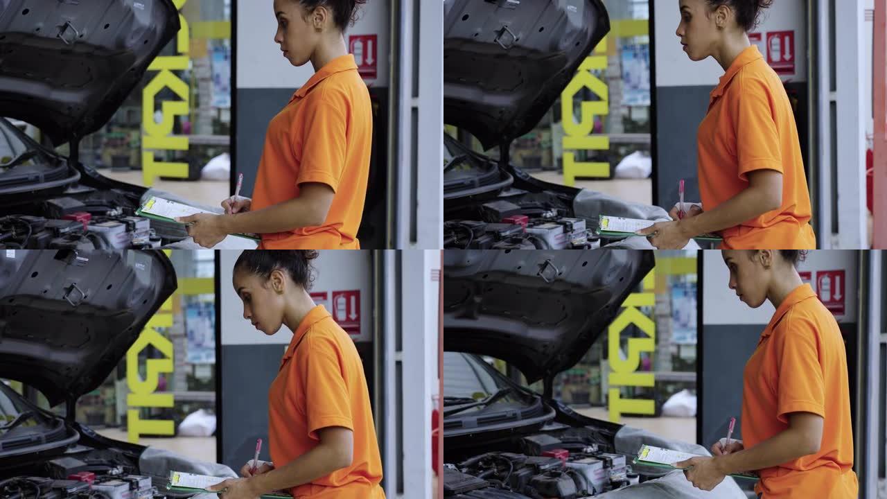 穿着橙色制服的女机械师在汽车服务站工作。专业技工在汽车维修车库工作。