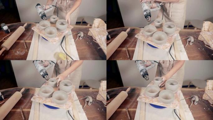 女人正在陶艺工作室用现代技术干燥机烘干陶罐