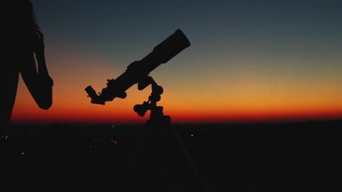 女孩通过望远镜看着黄昏的天空。