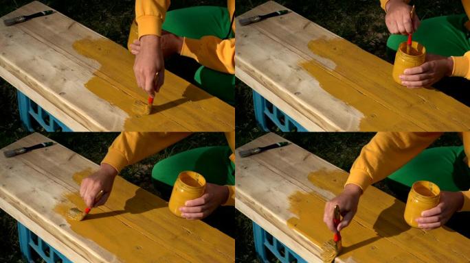 工人画家用黄色的画笔亲手绘画木材表面。特写。4K