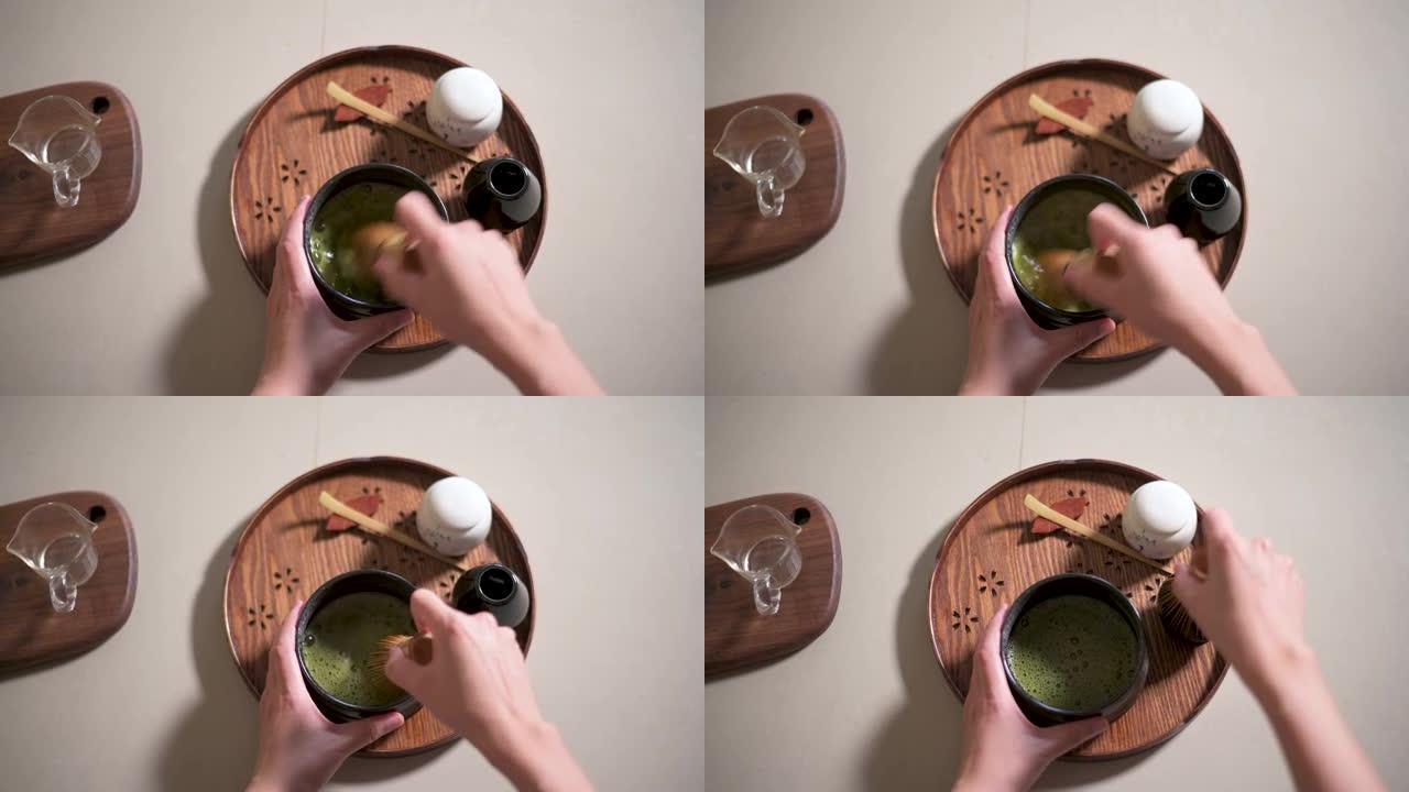 用竹制搅拌器制作抹茶绿茶的女人特写