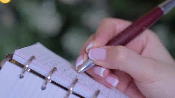 女人手握笔并在老式笔记本组织者中写字清单