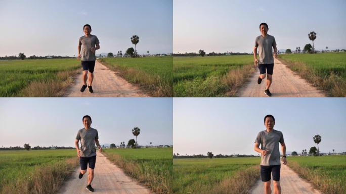 亚洲男子早上在稻田跑步，运动生活方式理念。