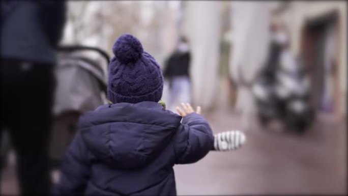 冬季，蹒跚学步的孩子在城市人行道上行走