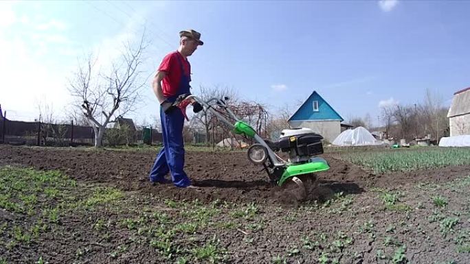 人类用耕作机在花园里耕种土地，为播种准备土壤