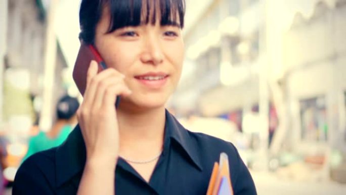 年轻的成年女商人在城市道路上白天使用智能手机。