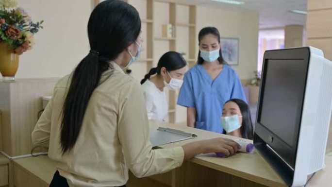 接待员戴着口罩，用红外线温度计测量温度，轮椅上的病人有姐姐和护士服务