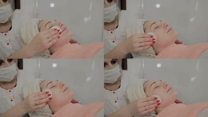 专业美容师用特殊的保湿湿巾摩擦女孩的脸。美容中的新概念