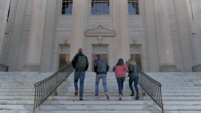 四名大学生走上楼梯前往公立大学的图书馆
