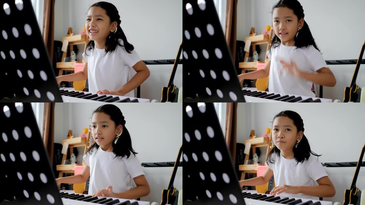 亚洲小女孩在家学习使用电子合成器键盘弹奏基础钢琴