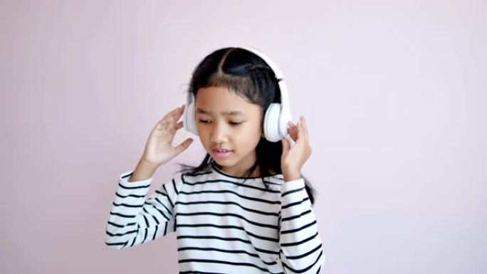 儿童使用白色耳机听音乐并根据音乐节奏摇摆