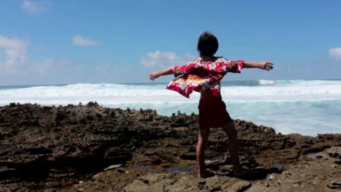 快乐的孩子们穿着五颜六色的夏威夷衬衫，享受观察毛里求斯附近一个岛屿岸边的大浪