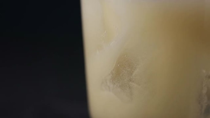 黄色鸡尾酒正在倒入装有冰块的玻璃杯中。