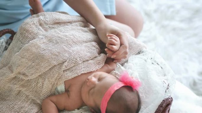 母亲牵手亚洲女性新生婴儿和阳光在早晨。可爱的小女孩三周大。医疗保健、爱情、关系概念