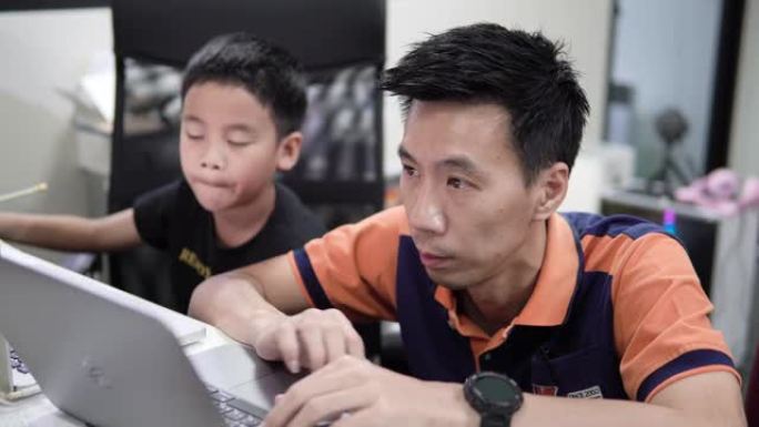 亚洲儿子在家和父亲一起上在线课。