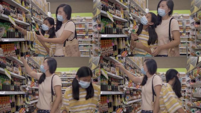 亚洲母亲和她的女儿戴着口罩，在封锁前的新型冠状病毒肺炎期间为家人囤积食物，生活方式理念。