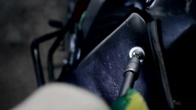 在您自己的车库中，用黑色塑料摩托车包裹螺栓的金属螺丝刀的第一人称视角的特写镜头，服务