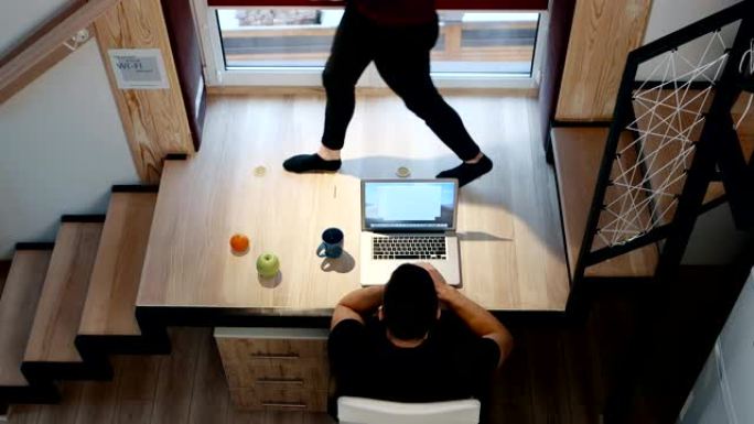 男人在笔记本电脑上工作，坐在桌子上的家庭办公室概念。顶视图。