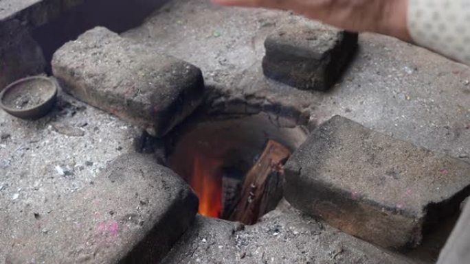 用木炭在装饰有四块砖的传统粘土炉中照亮红火。