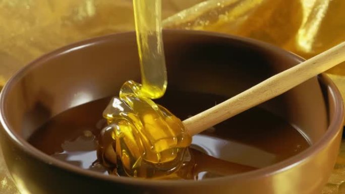 用勺子倒入碗中的蜂蜜慢动作。蜂蜜滴，健康有机浓蜂蜜。健康食品概念