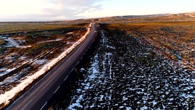 鸟瞰图被白雪皑皑的田野包围着，里面有一辆白色的汽车，在日落下-冰岛