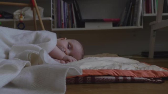 婴儿睡在铺着毯子的地板上