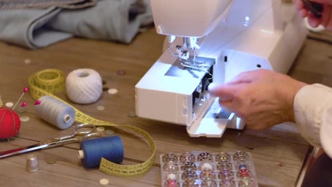 高级裁缝手准备电动缝纫机的线。