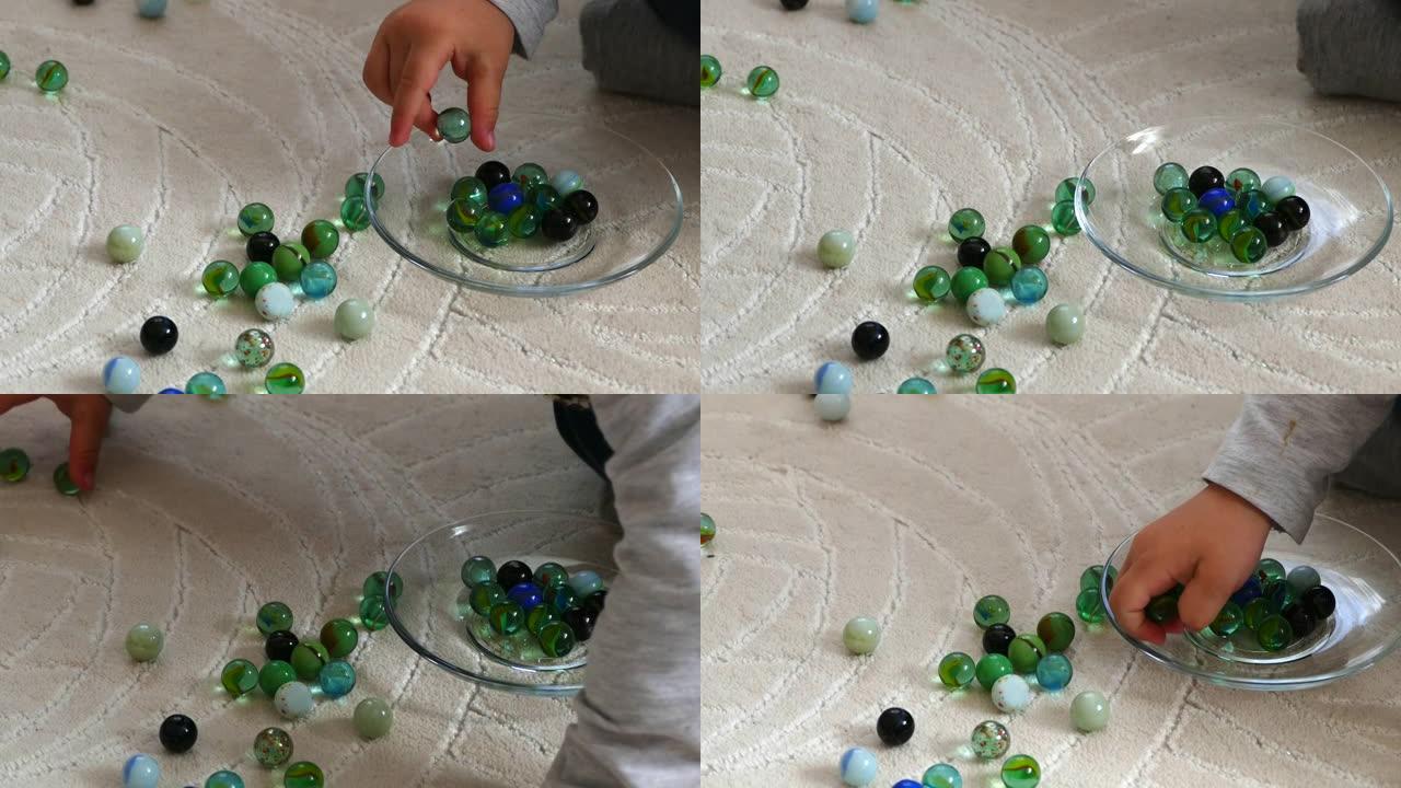 一个婴儿在地毯上玩玻璃弹珠和弹珠，彩色玻璃球和弹珠，