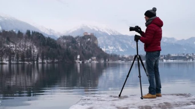 摄影师用三脚架拍摄冬湖的照片。