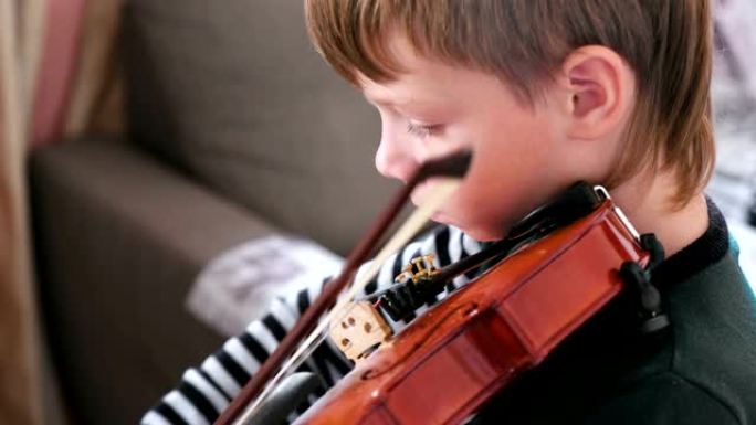 8岁的男孩正在学习拉小提琴。