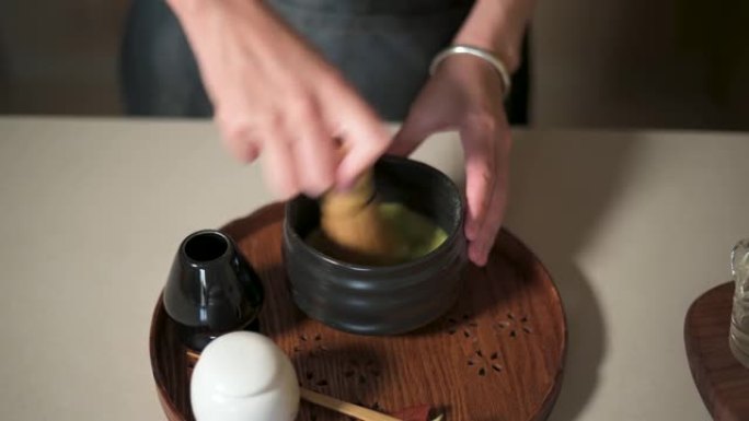 用竹制搅拌器制作抹茶绿茶的女人特写