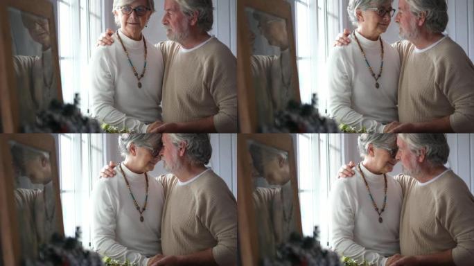 老年高加索夫妇在温柔的爱情时刻在家里亲吻和拥抱-年轻人的老年人生活方式-老人和女人在家里亲吻