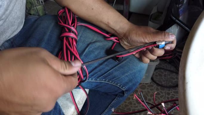 4k视频选择性聚焦中等镜头的男人用螺丝刀制作带扬声器连接器的音频扬声器电缆。技术人员手工制作声音扬声