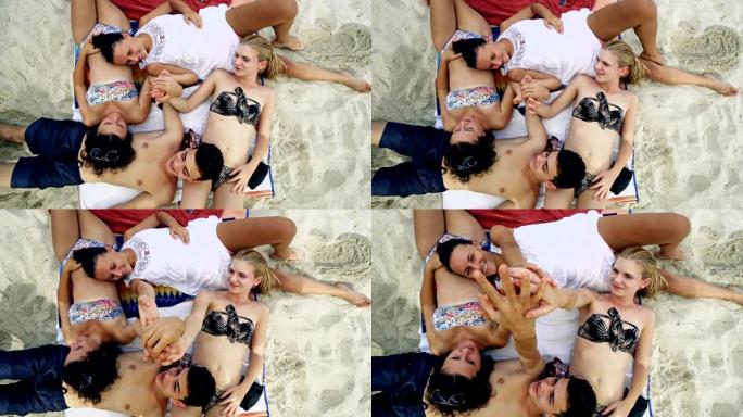 一群朋友在晴天躺在沙滩上。关于混血朋友和假期的概念