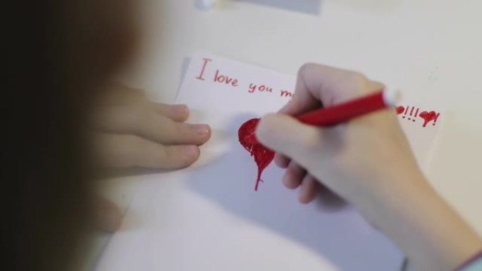 可爱的孩子在一张白纸上画一颗红色的心。