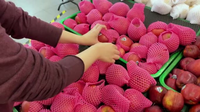 亚洲女性在超市选择苹果