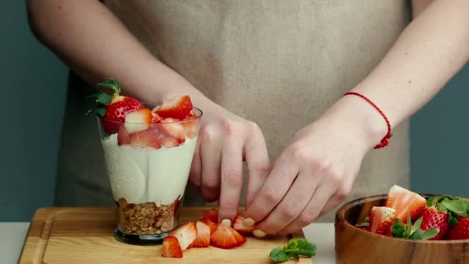 女性手准备酸奶与草莓良好的消化，胃肠道功能。夏季浆果，坚果，水果，奶制品放在桌子上。健康食品概念