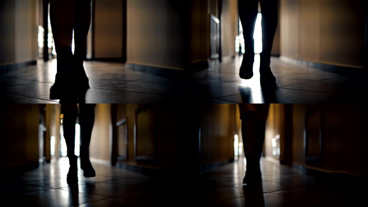 穿着靴子的女人沿着狭窄的黑暗通道走廊匆匆走近相机